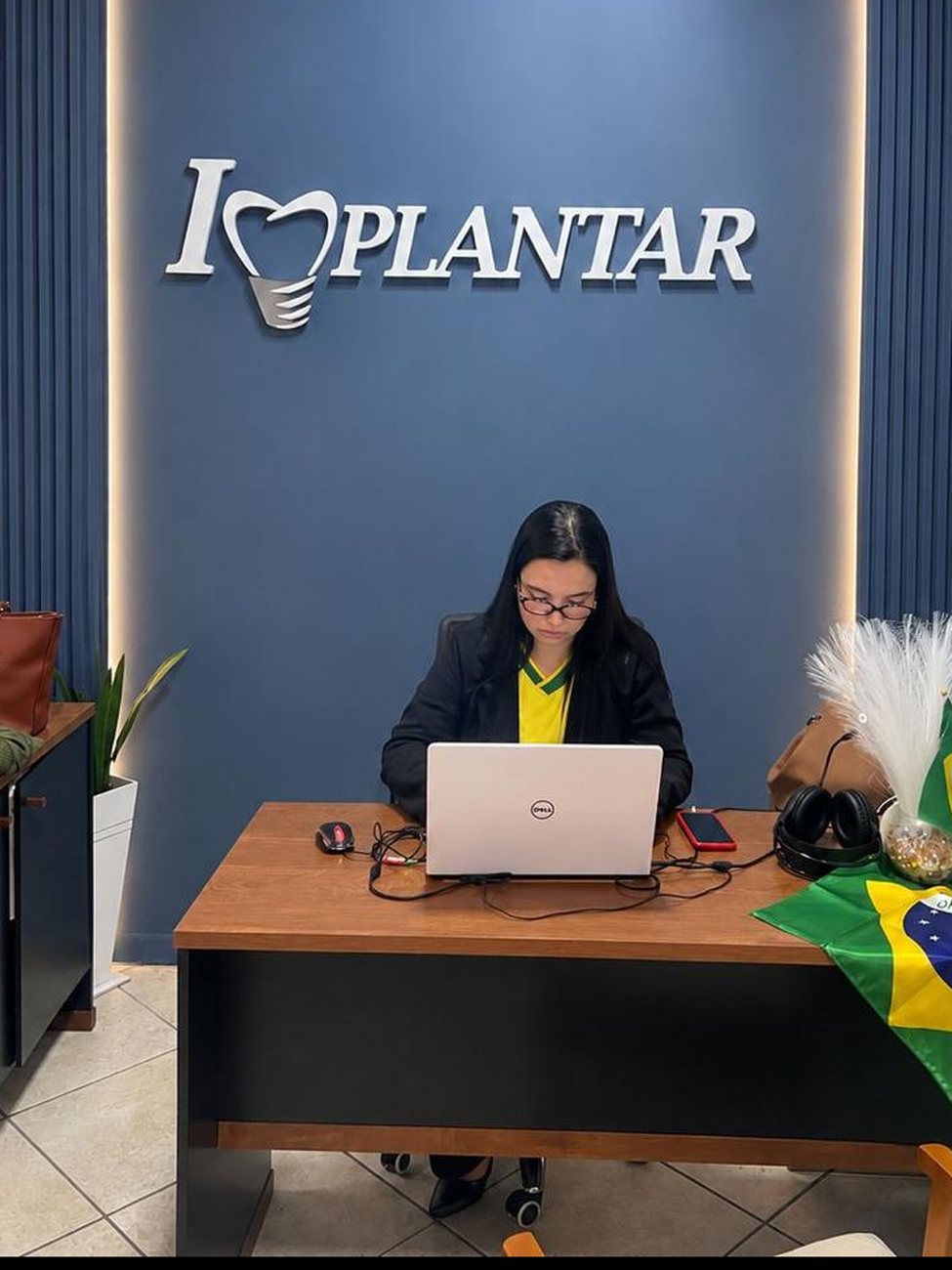 Recepção da Implantar com o logo na parede azul
